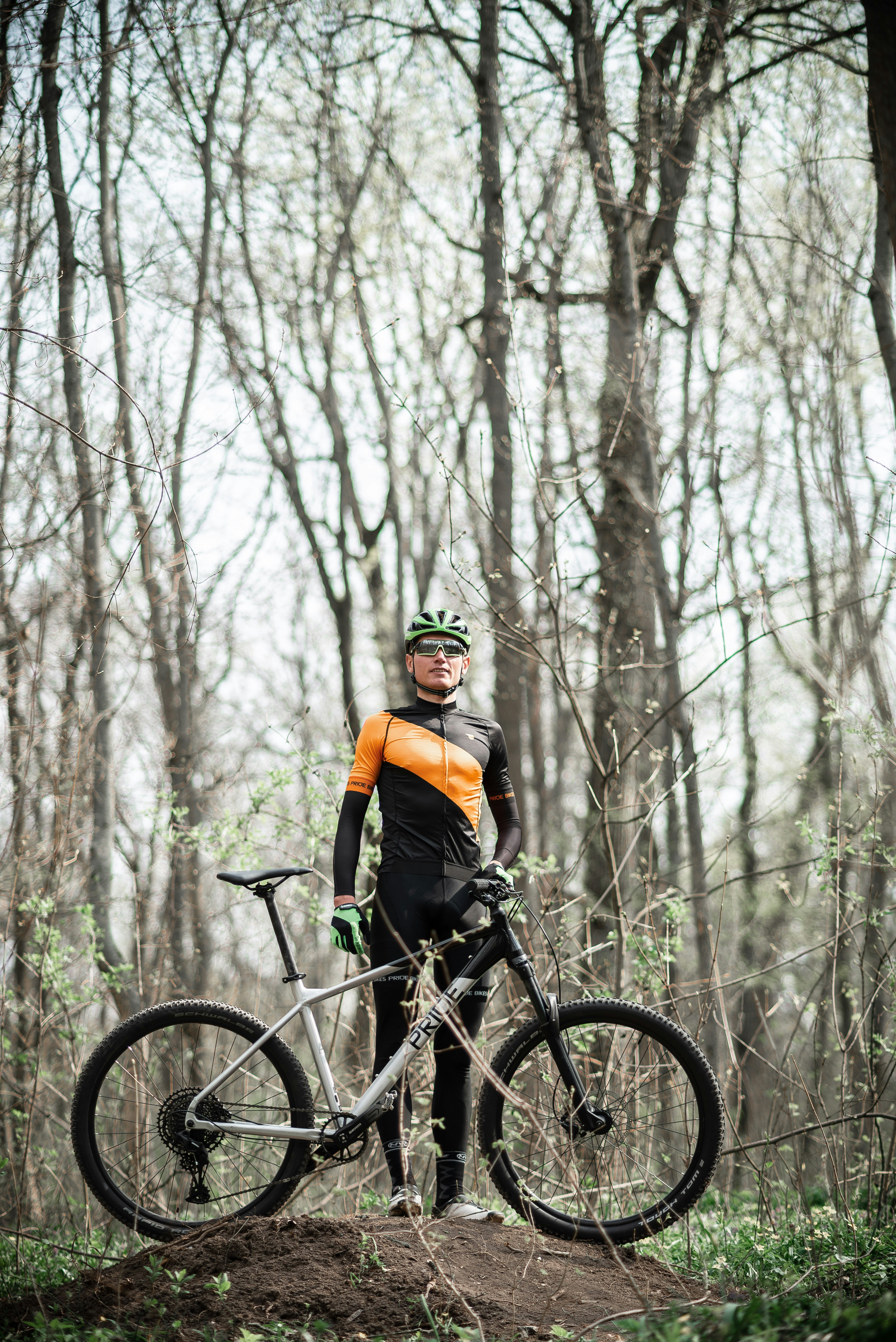 man in orange jacket riding on black mountain bike in forest during daytime